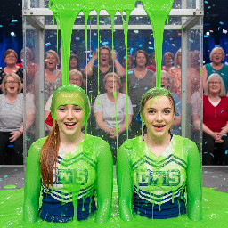 Two 18 year old cheerleaders, their hair in ponytail tied with ribbon. One has straight ginger hair, the other light brown hair. Looking directly at viewer, surprised giggling little smiles. Close shot.