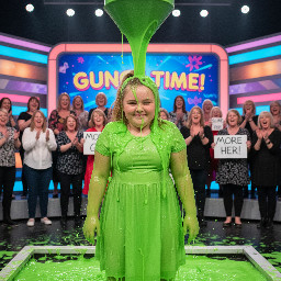 Tween cute girl with flat nose and prominent ears and honey blond hair that is partly in a ponytail and partly worn down, wearing a dress. Body is slightly curvy but not fat. Giggling in a shy manner.