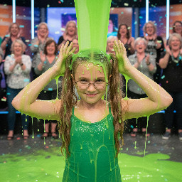 Young tween with long dirty-blond wavy hair in high pigtails. Wearing green spagetti strap shirt. Has glasses with rectangular small frames. Playful shy smile. Hands besides head. Photorealistic closeup.