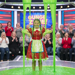 A early-teen girl wearing a short version of the little red riding hood costume (with the hood down and dress reaching down to knees) and low brown, not braided, slightly puffy, pigtails with ribbons. The gunge is getting everywhere on her. She does a thumbs-down gesture.