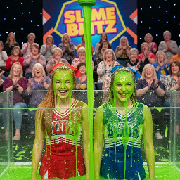 Two 18 year old cheerleaders, their hair in ponytail tied with ribbon. One has straight ginger hair, the other light brown hair. Looking directly at viewer. Medium close shot.